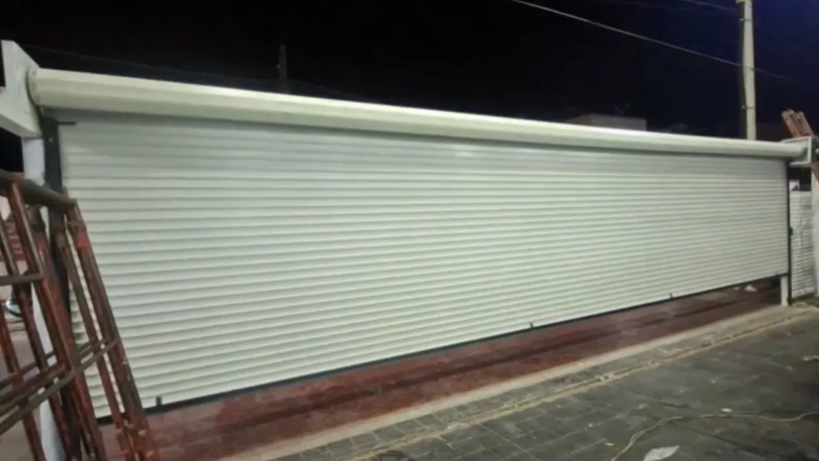 Cortina blanca de frente amplio recién instalada en un local, fotografiada de noche