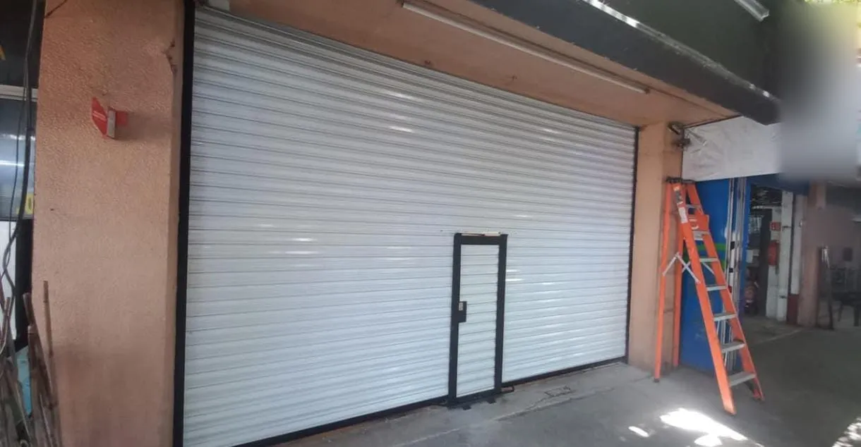 Cortina europea blanca con puerta peatonal integrada en la fachada de un local comercial