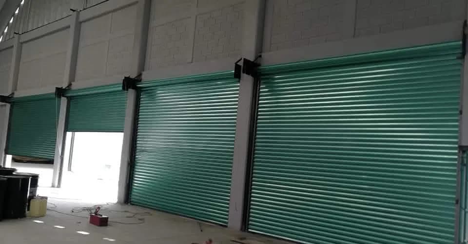 Serie de cortinas de acero verdes instaladas en los accesos de una bodega industrial